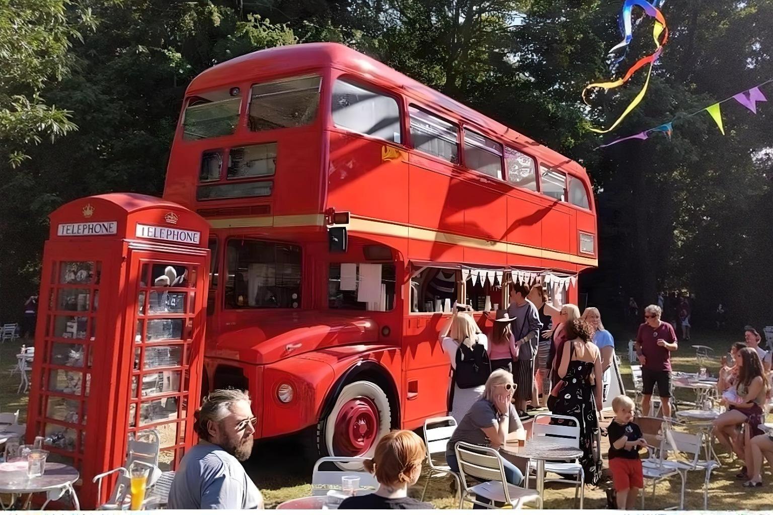 The bright red double-decker bus at Cedar Hollow Oxford with its serving hatch open, parked beside a red telephone box while guests sit at tables under the trees