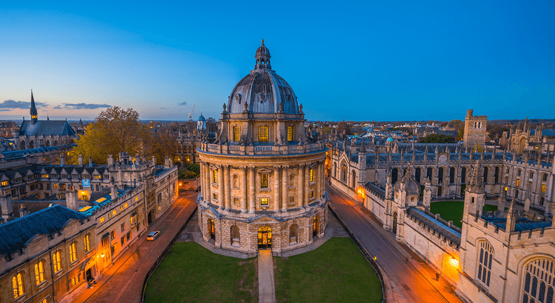 Oxford's Radcliffe Square at dusk with warmly lit college buildings