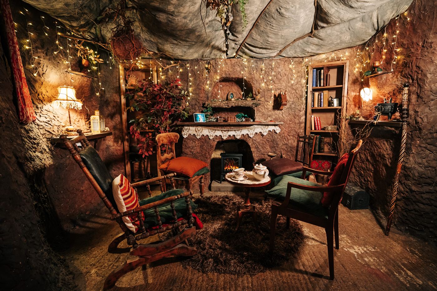 A cosy woodland retreat interior at Cedar Hollow with fairy lights, fireplace and rocking chair