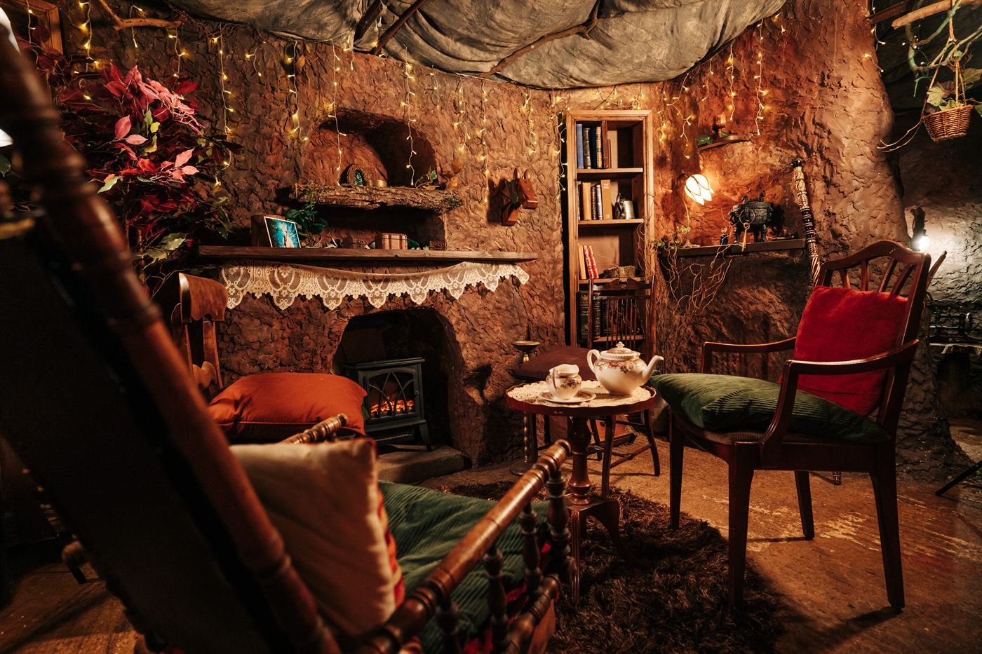 The cosy candle-lit interior of the Beaver's Den with stone fireplace, bookshelves and tea on the table